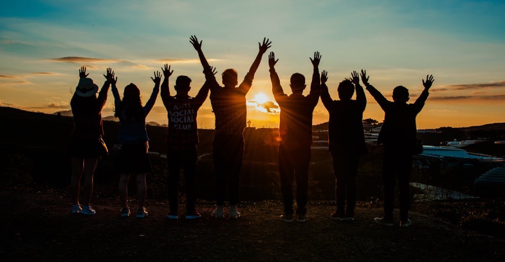 Grupa ludzi i ręce wyciągnięte do słońca